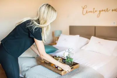 a woman standing on a bed with a tray of flowers at Hotel Penzion Kobala in Tolmin