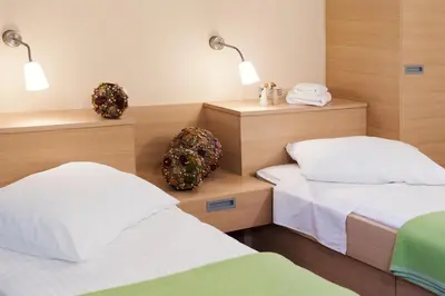 a bedroom with two beds and two lights on the wall at Hotel Penzion Kobala in Tolmin