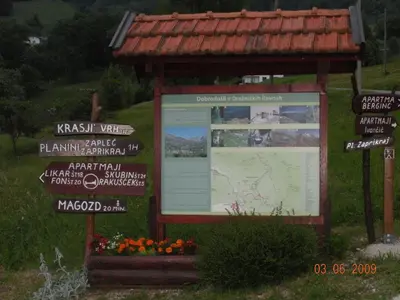 a sign in a field with some signs and flowers at Apartment Bric in Kobarid