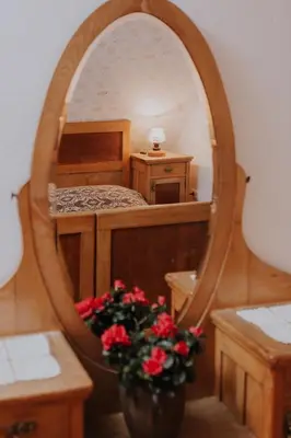 a bedroom with a bed and a mirror with flowers at Koroška hiša Pri lipi, Boutique hotel in Muta