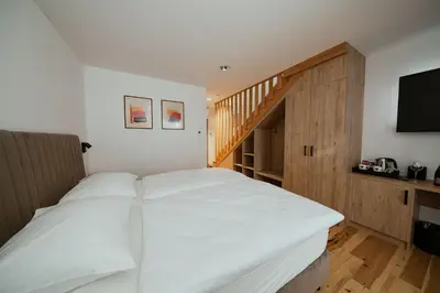 a bedroom with a white bed and a staircase at Rooms at Podlipje Estate in Tešanovci