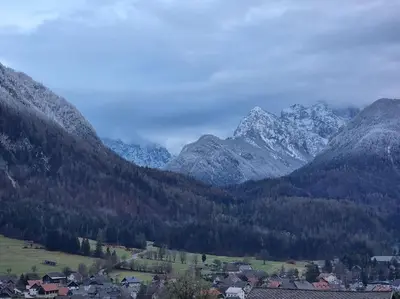 a town in front of a mountain range with snow at Comfy mountain nest in Mojstrana