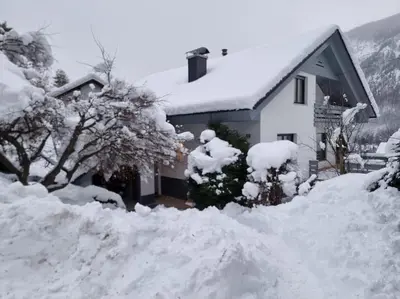 a snow covered house with a pile of snow at Comfy mountain nest in Mojstrana