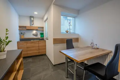 a kitchen and dining room with a wooden table and chairs at TEMPFER Apartments & Rooms with new WELLNESS in Rateče
