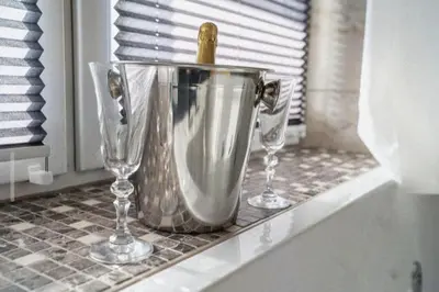 two wine glasses and a bucket on a counter at Apartma in wellness Čista fantazija in Velika Polana