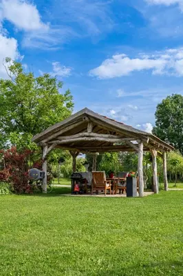 a wooden pavilion with a table and chairs in a park at Apartma in wellness Čista fantazija in Velika Polana