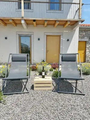 two chairs sitting in front of a house with a bottle of wine at Casa Matko in Kostanjevica na Krasu