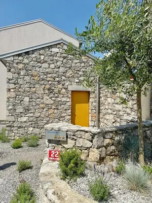 a stone building with a yellow door in a yard at Casa Matko in Kostanjevica na Krasu