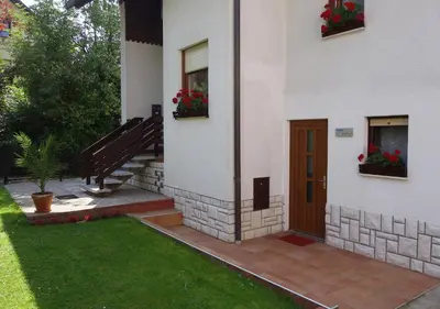 a house with a staircase and a door and flowers at Sobe Vera in Bovec