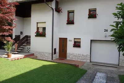 a white house with two garage doors and flowers at Sobe Vera in Bovec