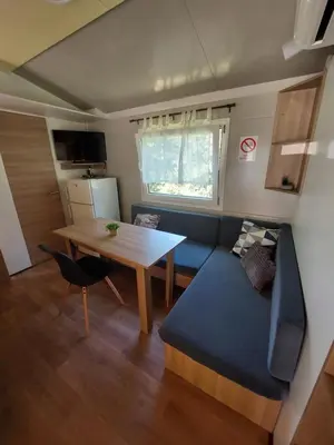 a living room with a table and a blue couch at Mobilna hiška Lebanč in Breginj
