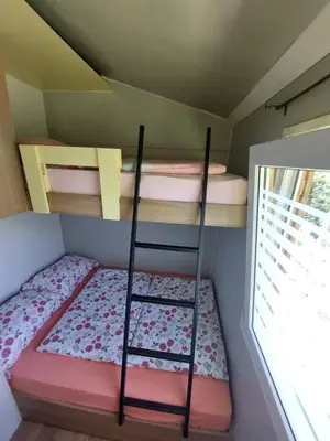 a small room with two bunk beds and a ladder at Mobilna hiška Lebanč in Breginj