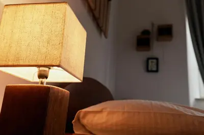 a lamp sitting on a table next to a bed at Rooms & Restaurant Ostarija in Dolenjske Toplice