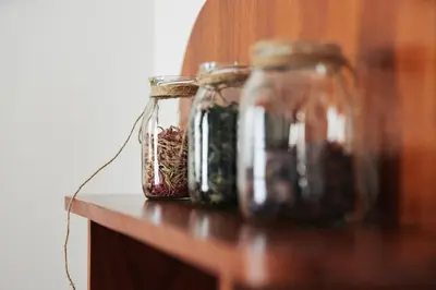 four glass jars sitting on a wooden shelf at Rooms & Restaurant Ostarija in Dolenjske Toplice