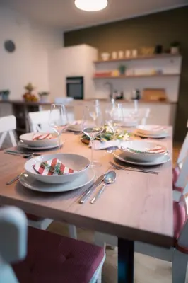 a wooden table with plates and wine glasses on it at Peak Haven apartments, Pohorje in Pohorje