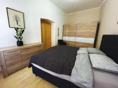 a bedroom with a large bed with a wooden headboard at Viktorija City Center Apartment in Ljubljana
