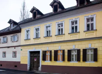 a yellow building with windows and a door at Viktorija City Center Apartment in Ljubljana