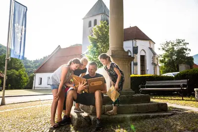 a group of people standing around a man sitting on a bench at Rooms Savinja in Laško