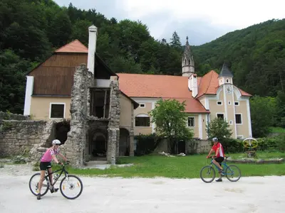 two people riding bikes in front of a church at Rooms Savinja in Laško
