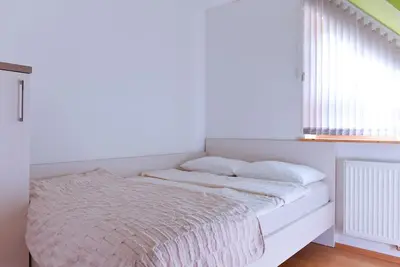 a white bed in a room with a window at Apartment Bohinjko in Bohinj