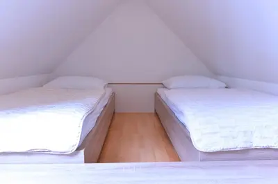 two beds in a room with white sheets at Apartment Bohinjko in Bohinj