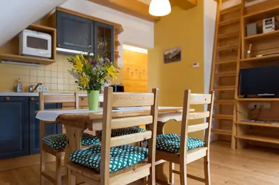 a kitchen with a wooden table with chairs and a television at Alpine Spot in Kranjska Gora