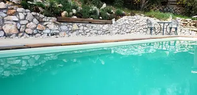a swimming pool with a chair next to a stone wall at Holiday Home Katričnek in Bohinjska Bela
