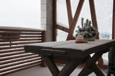 a wooden bench sitting on a balcony with a christmas tree at Holiday Home Razglednik in Logatec