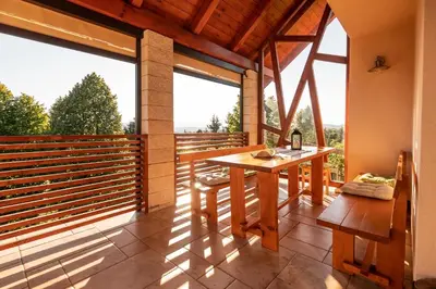a balcony with a wooden table and large windows at Holiday Home Razglednik in Logatec