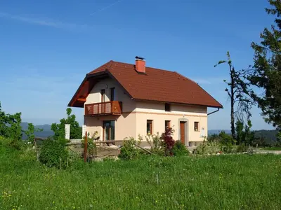 a house with a red roof on a green field at Holiday Home Razglednik in Logatec