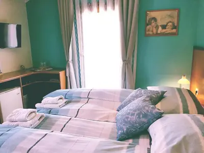 a bedroom with a bed with two pillows and a window at Rooms Leban in Šempas