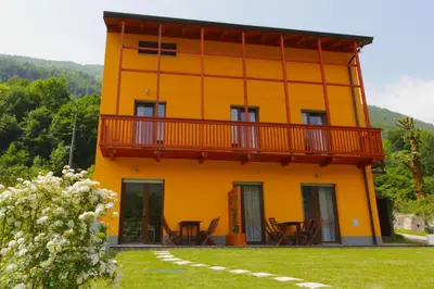 a yellow house with a balcony on top of it at Apartments Maligoj in Tolmin