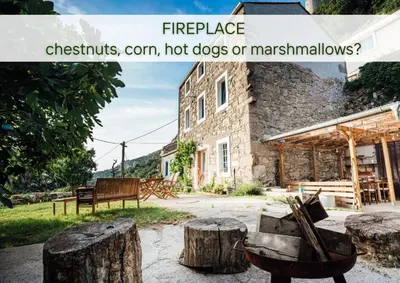 a building with a bunch of logs in front of it at Villa Lapis - stone house with amazing view in Črni Kal