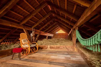 a wooden chair sitting in a barn with hay at Hay barn unique experience Visole in Slovenska Bistrica