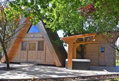 a small house with a triangular roof with a tree at Luxury Wellnes Glamping Cottage - Salvus in Lendava