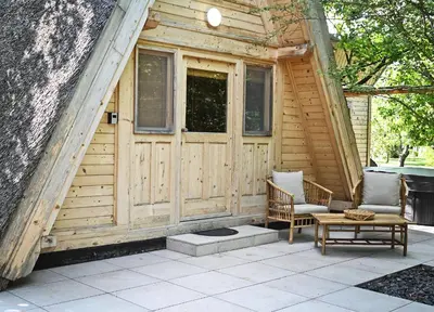 a wooden cabin with two chairs and a table at Luxury Wellnes Glamping Cottage - Salvus in Lendava