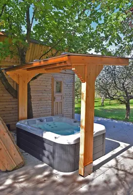 a hot tub under a wooden pergola at Luxury Wellnes Glamping Cottage - Salvus in Lendava