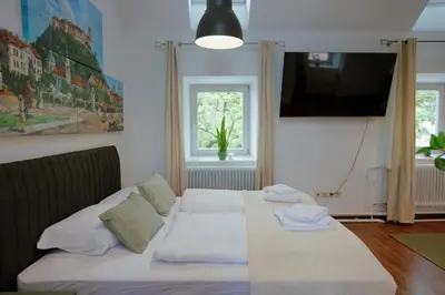 a bedroom with a bed with white sheets and a television at BRIDGE apartments in Ljubljana