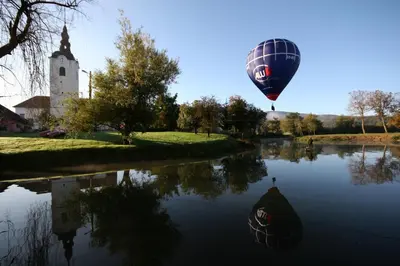 a hot air balloon flying over a river with a church at Apartment Na Krki in Kostanjevica na Krki