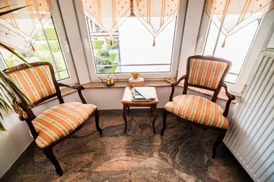 two chairs and a table in a room with two windows at Apartment Joga in Rečica ob Savinji