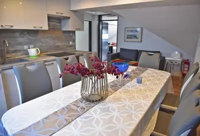 a dining room table with a vase of flowers on it at Salvus Apartma - Sun & Moon in Lendava