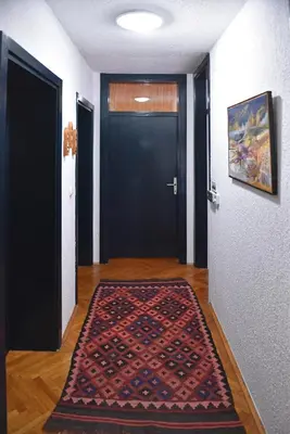 a hallway with a black door and a rug on the floor at Salvus Apartma - Sun & Moon in Lendava