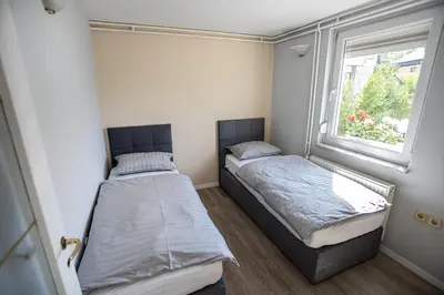 two beds in a small room with a window at Apartments Bells of Ljubljana - 3 cosy apartment Private Free Parking in Ljubljana