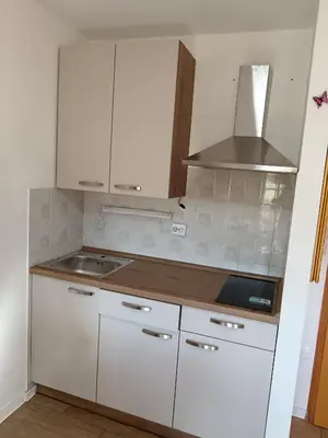 a small kitchen with white cabinets and a sink at Apartma Trobentica 15 in Moravske Toplice