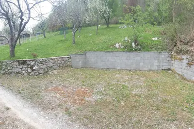 a stone retaining wall in a yard next to a field at moderno opremljena hiša z odmaknjeno lokacijo in Dolenjske Toplice