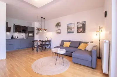 a living room with a blue couch and a kitchen at Sunrise Bohinj Apartment in Bohinj