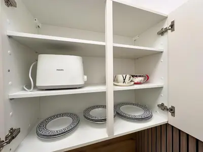 a kitchen pantry with plates and a microwave at Apartments Adamas in Celje