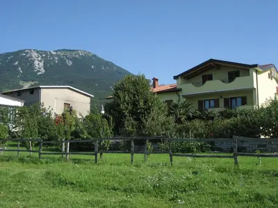 a house in a field with a mountain in the background at Turistična kmetija Pri Rebkovih in Ajdovščina