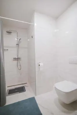 a white bathroom with a shower and a toilet at Apartment Skala with Magnificent view in Rečica ob Savinji