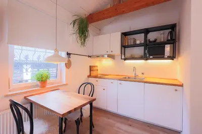 a kitchen with white cabinets and a wooden table at Studio Apartment Jož' in Spodnja Lipnica